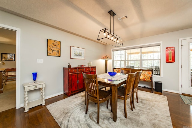 dining room featuring a textured ceiling, dark hardwood / wood-style floors, and a chandelier