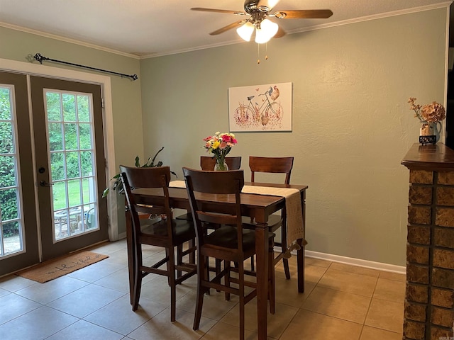 tiled dining space featuring ceiling fan, ornamental molding, and french doors