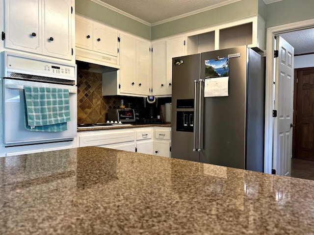 kitchen with oven, dark stone countertops, high quality fridge, and white cabinetry