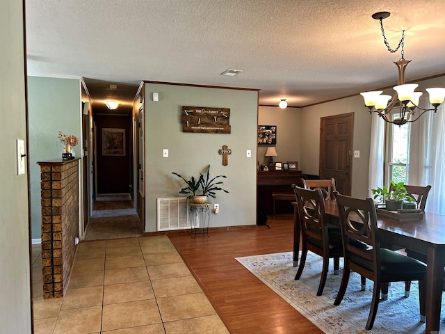 dining space featuring hardwood / wood-style floors, crown molding, a textured ceiling, and a chandelier