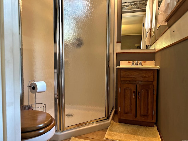 bathroom featuring toilet, tile patterned flooring, walk in shower, and vanity