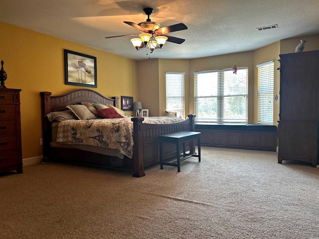 carpeted bedroom featuring ceiling fan and a textured ceiling