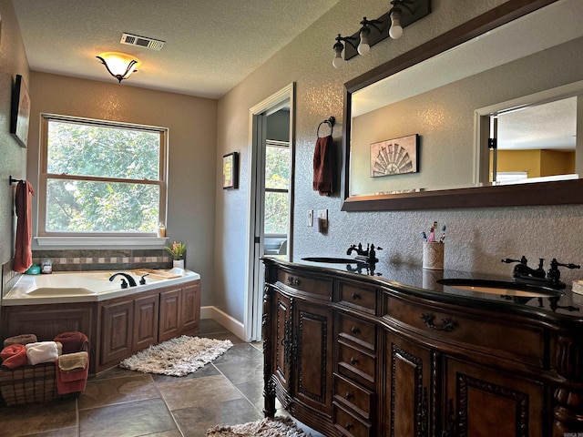 bathroom with tile patterned flooring, a tub to relax in, a textured ceiling, and vanity