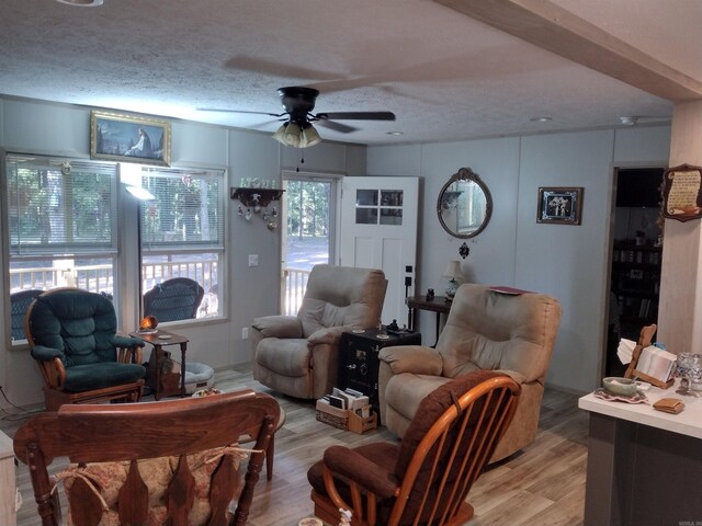 living room featuring a textured ceiling, light hardwood / wood-style flooring, and ceiling fan