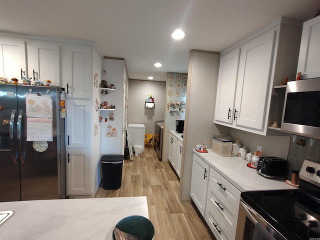 kitchen featuring separate washer and dryer, stainless steel appliances, light hardwood / wood-style flooring, and white cabinets