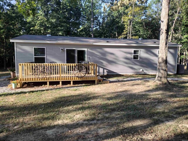 rear view of house featuring a wooden deck and a lawn