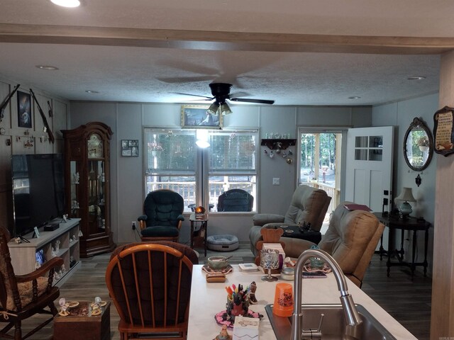 living room with ceiling fan, a textured ceiling, and hardwood / wood-style floors