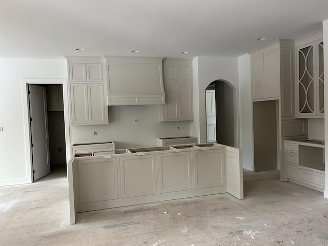 kitchen featuring arched walkways, wall chimney exhaust hood, and recessed lighting