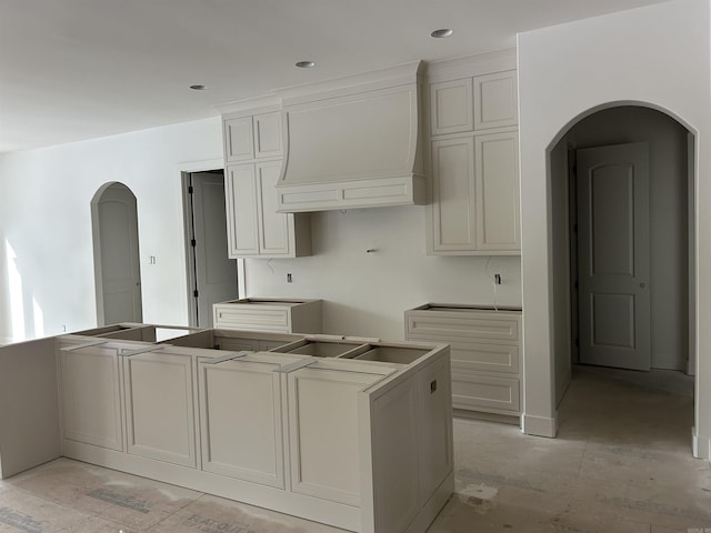 kitchen with arched walkways, custom exhaust hood, and recessed lighting