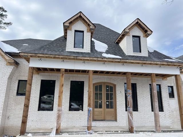 view of front of house featuring covered porch, roof with shingles, and brick siding