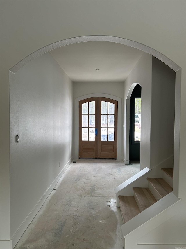 foyer featuring stairs, arched walkways, and french doors