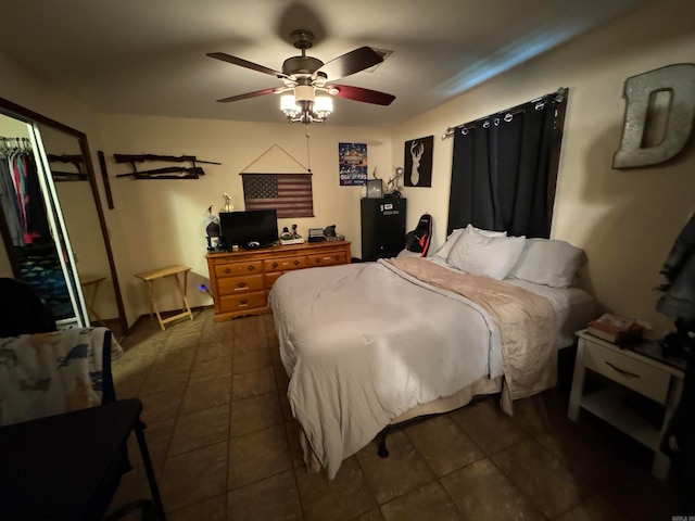 bedroom with ceiling fan, dark tile patterned flooring, and a closet