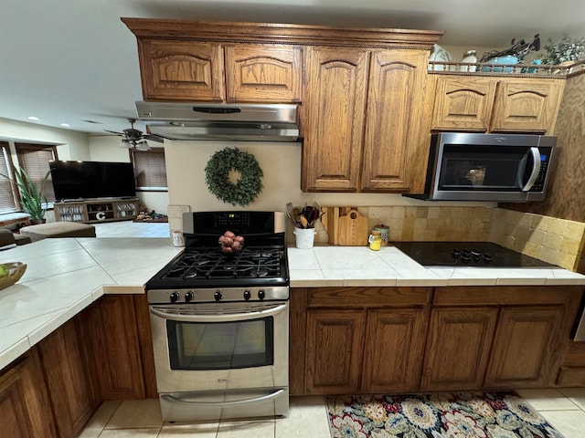 kitchen featuring appliances with stainless steel finishes, tile countertops, ceiling fan, and light tile patterned floors