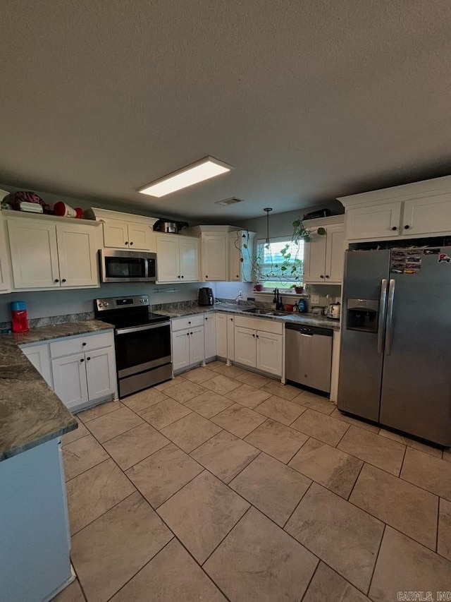 kitchen featuring white cabinetry, sink, decorative light fixtures, light tile patterned flooring, and stainless steel appliances