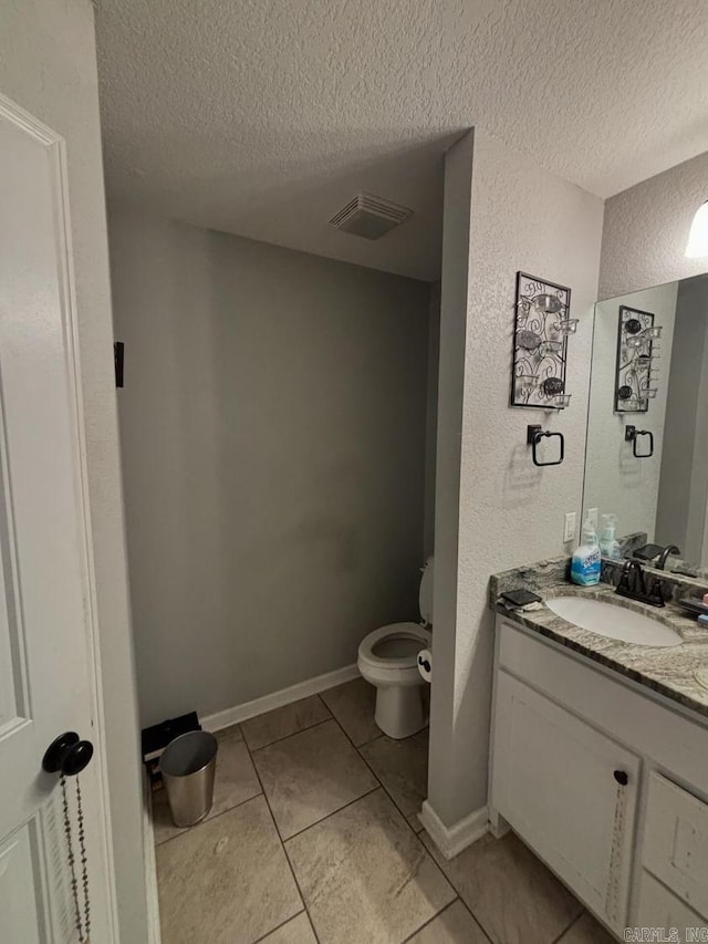 bathroom with tile patterned flooring, a textured ceiling, vanity, and toilet