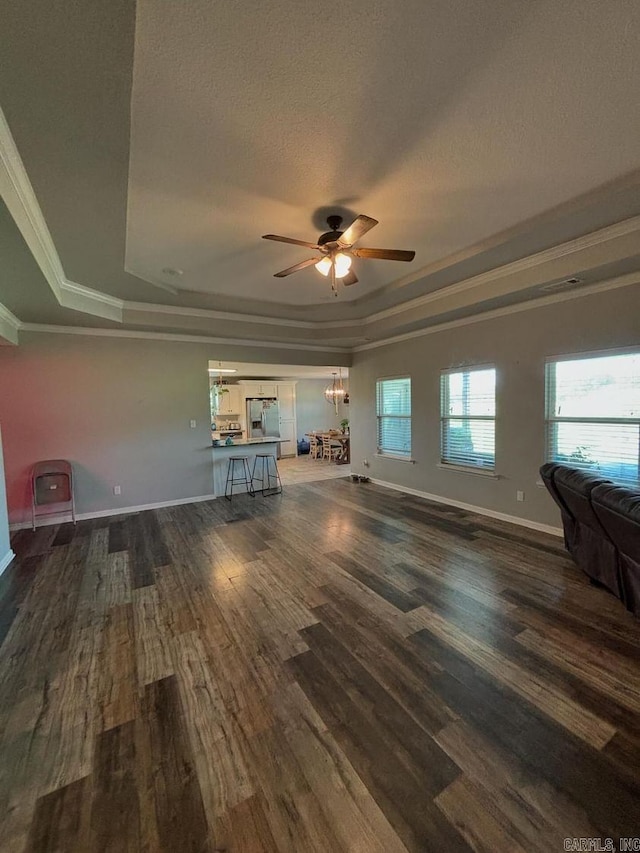 unfurnished living room with a tray ceiling, ceiling fan, ornamental molding, and wood-type flooring