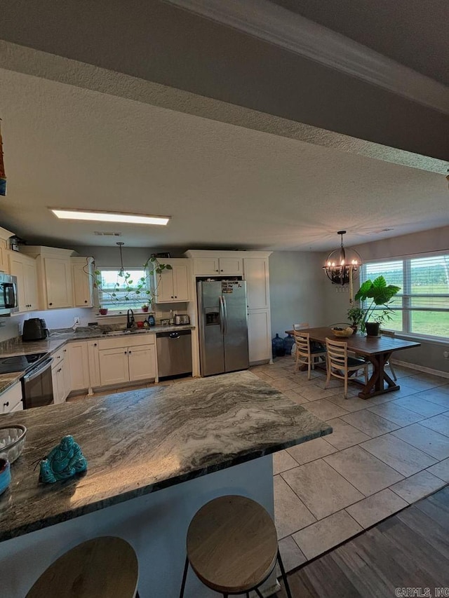 kitchen featuring sink, an inviting chandelier, decorative light fixtures, appliances with stainless steel finishes, and white cabinetry