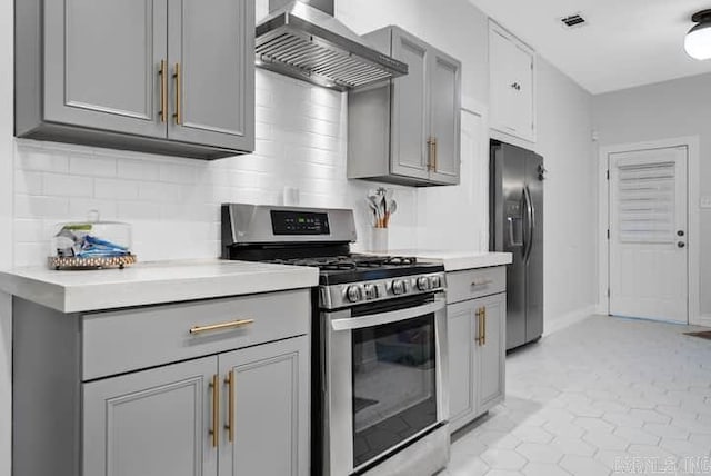 kitchen with gray cabinetry, stainless steel appliances, light tile patterned flooring, and wall chimney exhaust hood