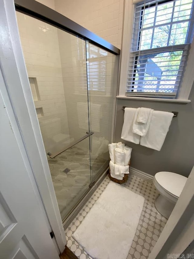 bathroom with toilet, walk in shower, and tile patterned flooring