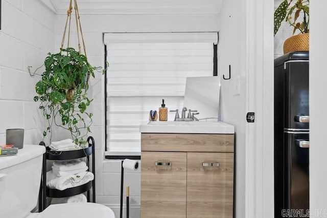 bathroom with tile walls, crown molding, vanity, and toilet