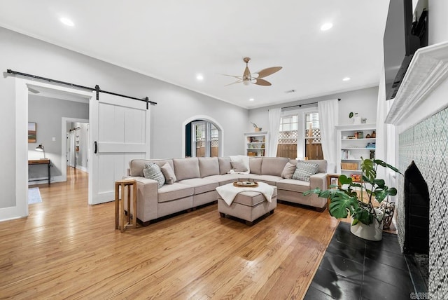 living room with ceiling fan, light hardwood / wood-style flooring, and a barn door