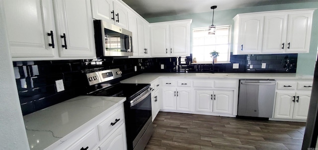 kitchen with appliances with stainless steel finishes, white cabinets, decorative light fixtures, and a sink