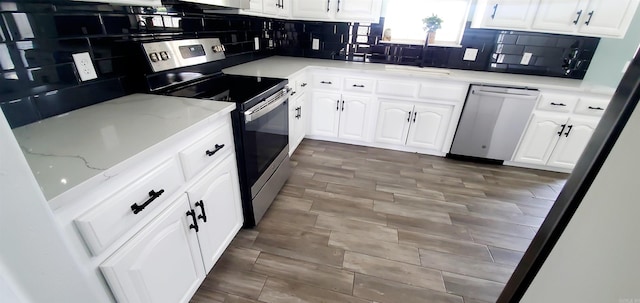 kitchen with stainless steel appliances, white cabinets, a sink, and decorative backsplash