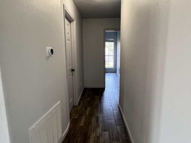 hallway with baseboards, visible vents, and dark wood-style flooring