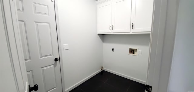 washroom featuring hookup for an electric dryer, dark tile patterned floors, washer hookup, baseboards, and cabinet space