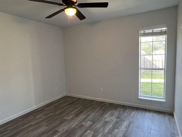 empty room featuring dark wood finished floors, a ceiling fan, and baseboards