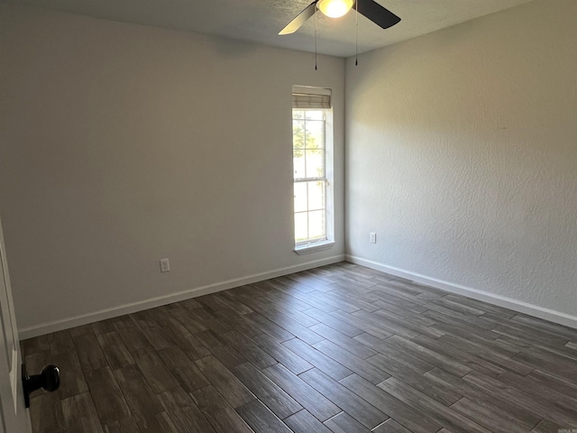 unfurnished room with a ceiling fan, baseboards, and dark wood-style flooring