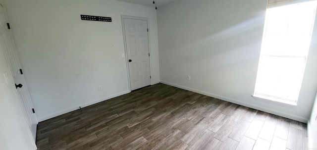 empty room with baseboards and dark wood finished floors