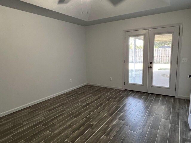 spare room with ceiling fan, dark hardwood / wood-style floors, french doors, and a raised ceiling