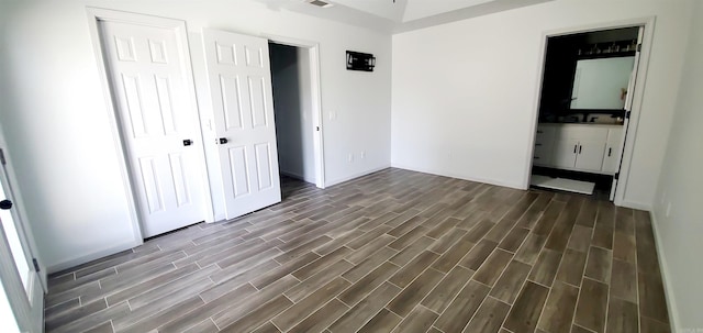 unfurnished bedroom with sink, ensuite bathroom, and wood-type flooring