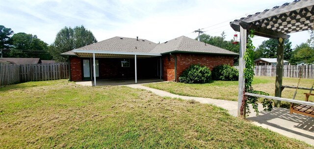 back of property featuring brick siding, a lawn, a patio area, a pergola, and a fenced backyard