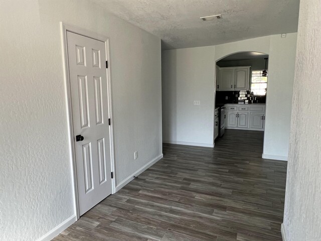 empty room with a textured ceiling and dark hardwood / wood-style floors