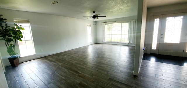 foyer entrance with dark wood-style flooring, a healthy amount of sunlight, visible vents, and a textured ceiling