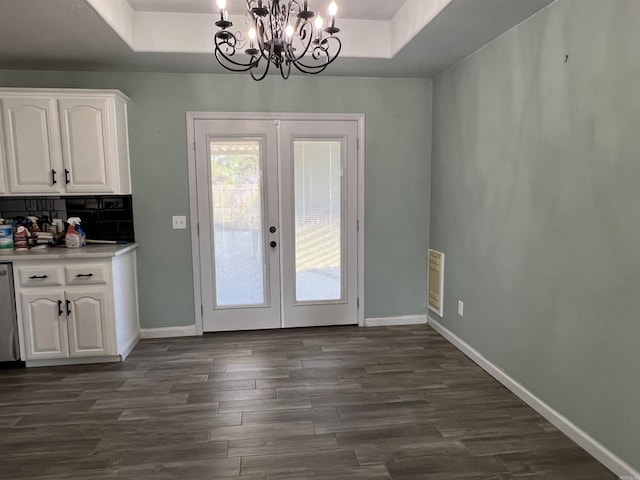 doorway to outside with dark wood-style floors, baseboards, a tray ceiling, and french doors