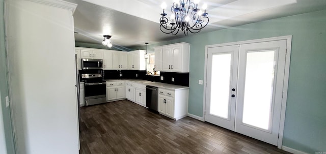 kitchen with french doors, dark wood-style flooring, stainless steel appliances, hanging light fixtures, and white cabinetry