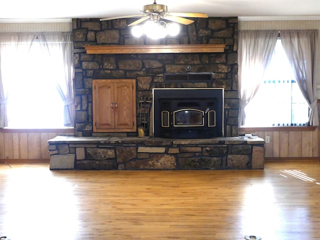 1105 Crescent Dr, Mena, AR 71953 - living area featuring light wood-style floors, plenty of natural light, ceiling fan, a wood stove, and wooden walls