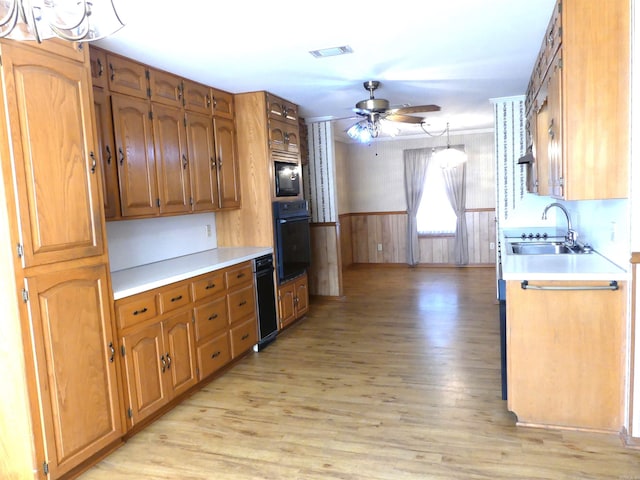1105 Crescent Dr, Mena, AR 71953 - kitchen featuring black oven, a sink, light wood finished floors, light countertops, and a wainscoted wall