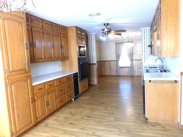 kitchen featuring light wood-type flooring, black oven, sink, and ceiling fan