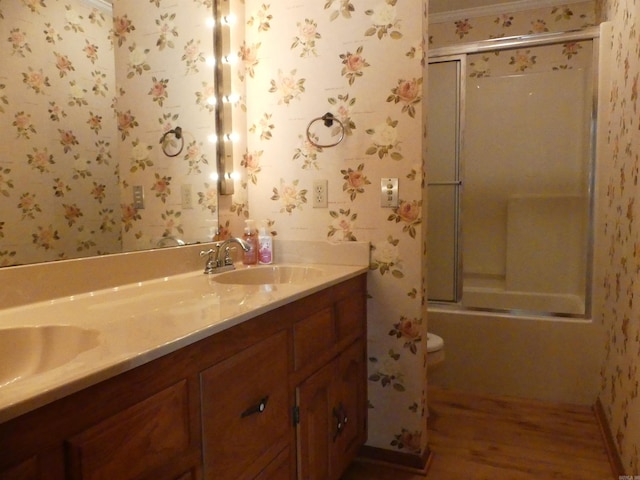 full bathroom featuring shower / bath combination with glass door, hardwood / wood-style floors, vanity, crown molding, and toilet