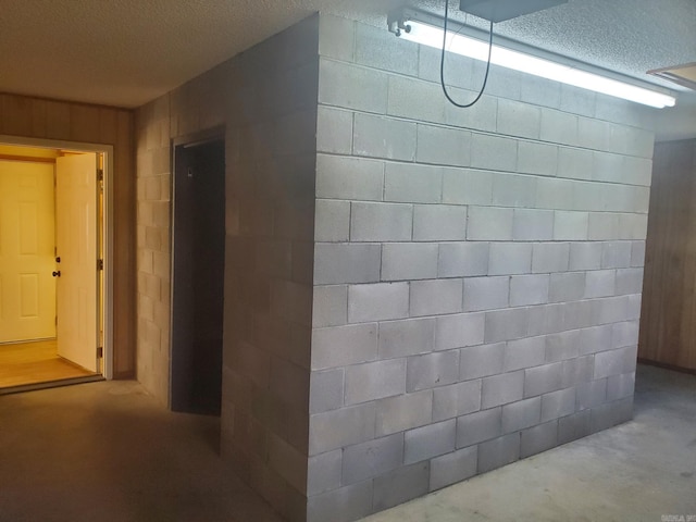 1105 Crescent Dr, Mena, AR 71953 - hall with concrete block wall, a textured ceiling, and concrete flooring