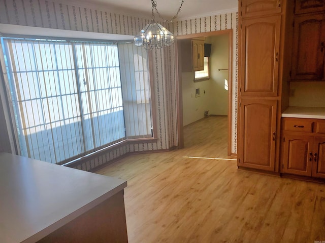 unfurnished dining area with a notable chandelier, light hardwood / wood-style flooring, and ornamental molding