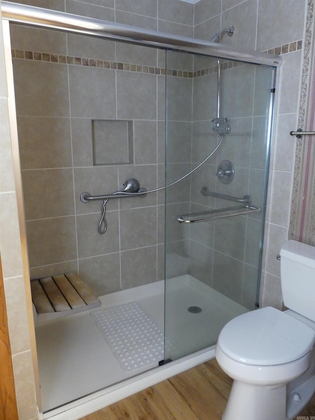 bathroom with wood-type flooring, a shower with shower door, and toilet