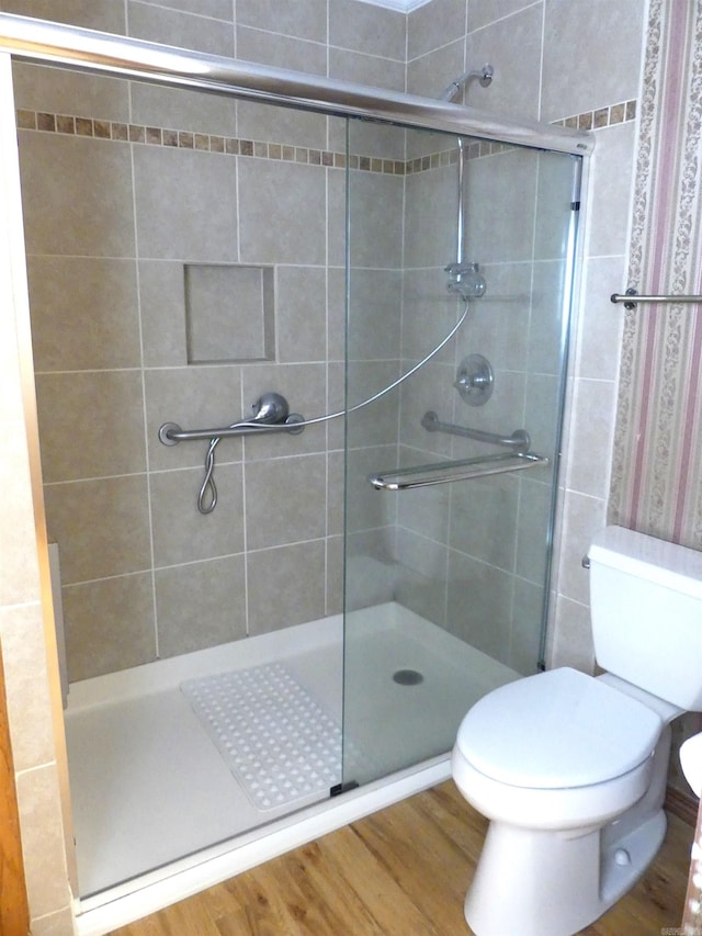 bathroom featuring a shower with shower door, toilet, and hardwood / wood-style flooring