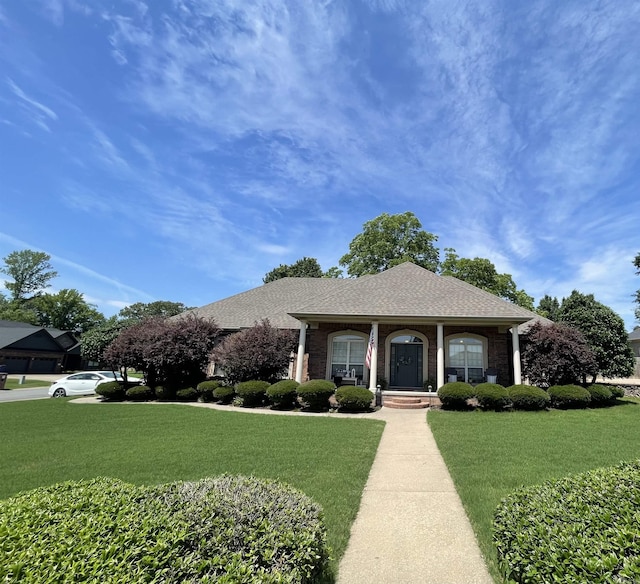 view of front of house featuring brick siding, a front lawn, and roof with shingles