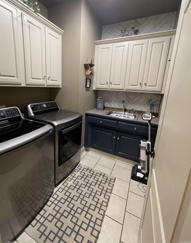 laundry room featuring cabinet space, washing machine and dryer, light tile patterned floors, and a sink