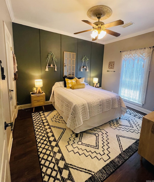 bedroom with ornamental molding, wood finished floors, visible vents, and baseboards